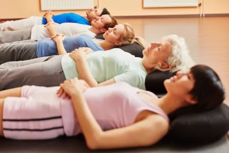 Senior und Gruppe beim Autogenen Training zur Entspannung