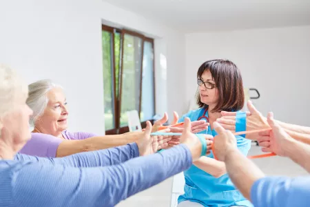 Physiotherapeut, der eine Ergotherapie mit elastischem Band mit Senioren durchführt.