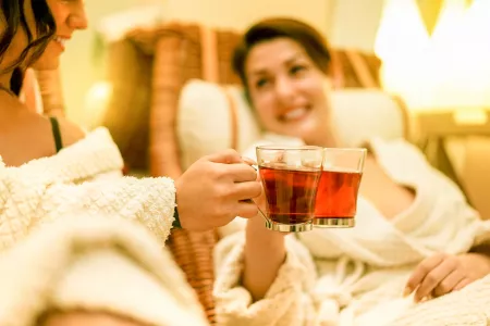 Junge Frauen genießen toastenden Infusionstee während des Behandlungstags im Kurort - F.-X.-Mayr-Kur.