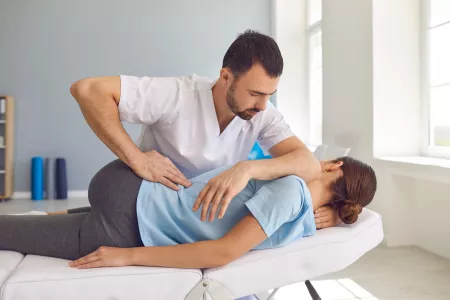 Junger männlicher Arzt, Chiropraktiker oder Osteopath behandelt eine Frau mit manueller Therapie