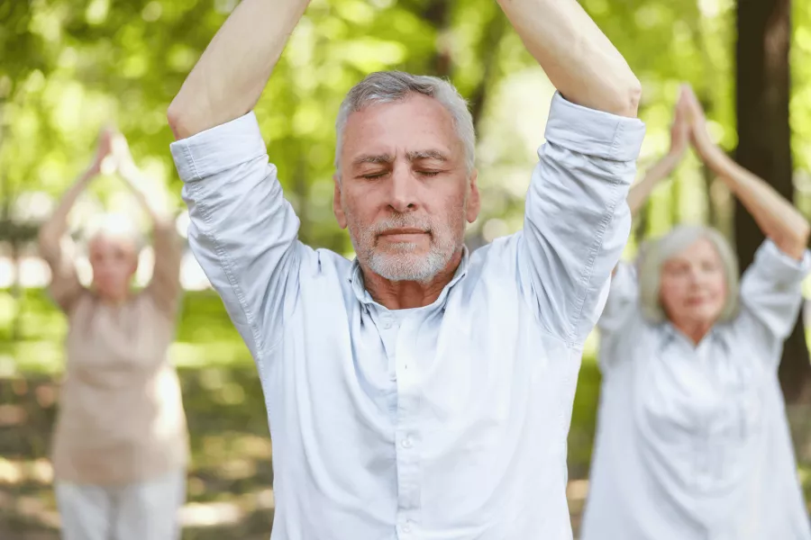 Gelassener reifer Mann beim Praktizieren von Qigong im Park