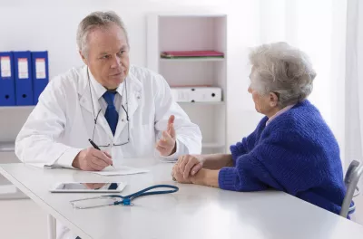 Arzt spricht mit seiner älteren Patientin im Büro