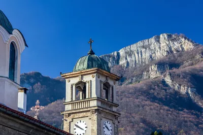 Teilansicht des Glockenturms und der Kuppeln der christlichen Kirche in der Stadt Teteven, Bulgarien. Im Hintergrund ist einer der Gipfel des Balkangebirges zu sehen.