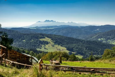 ein braunes Gebäude vor einer grünen Wiese und Bergen in der Ferne