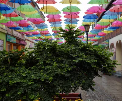 Bunte Schirme und Grünpflanze in Fußgängerzone von Bad Polzin