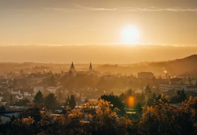 die Sonne geht über einer Stadt in der Ferne unter