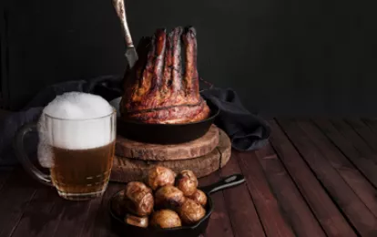 Gebratene Schweinerippchen, gebackene Kartoffeln und ein Becher kaltes Bier