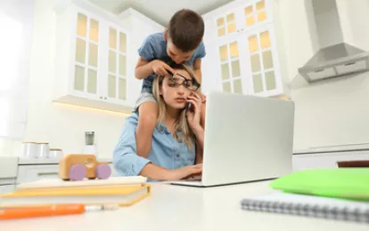 Kleiner Junge, der Mutter bei der Arbeit in der Küche stört